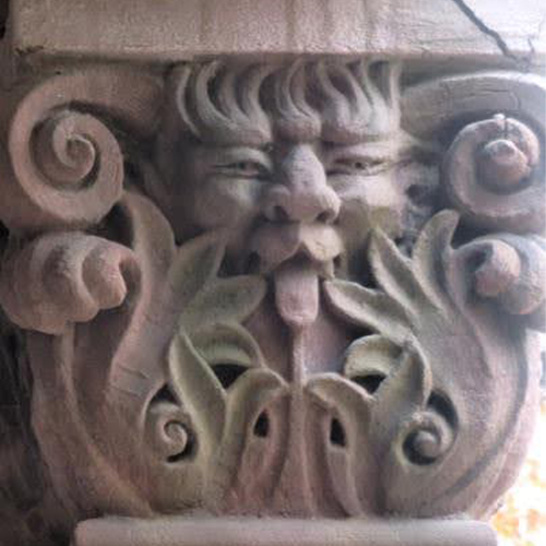A stone carving of a face with a tongue sticking out, showcasing a playful and mischievous expression.