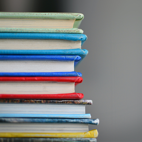 the image shows a stack of  six books with colorful cover edges showing against a gray background