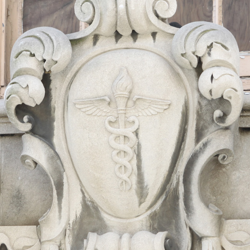 A carving above the entrance of the Health Sciences Library, depicting a caduceus on a shield