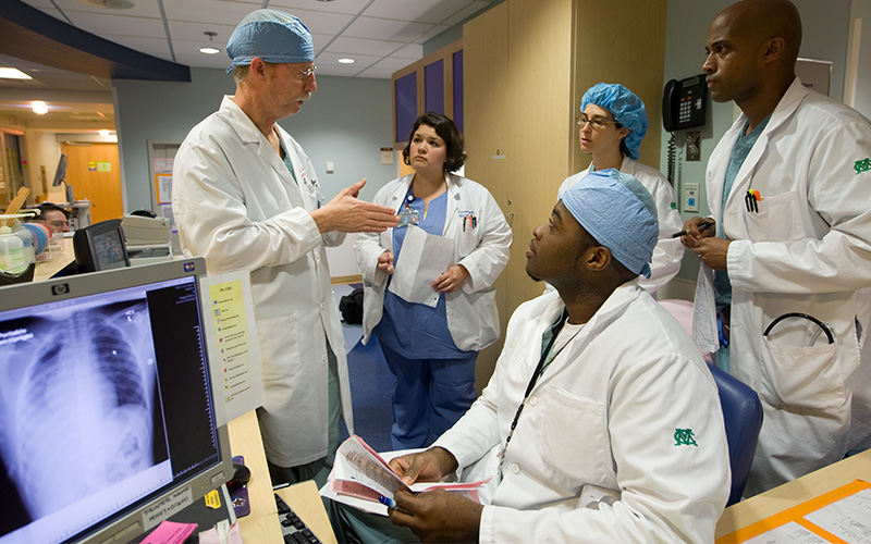 A group of doctors are gathered around a computer have a discussion.