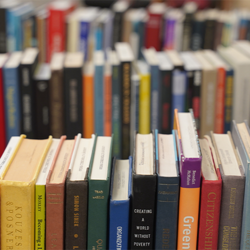 a row of books of varying colors is shown with the front row in perfect focus and the two rows behind blurry