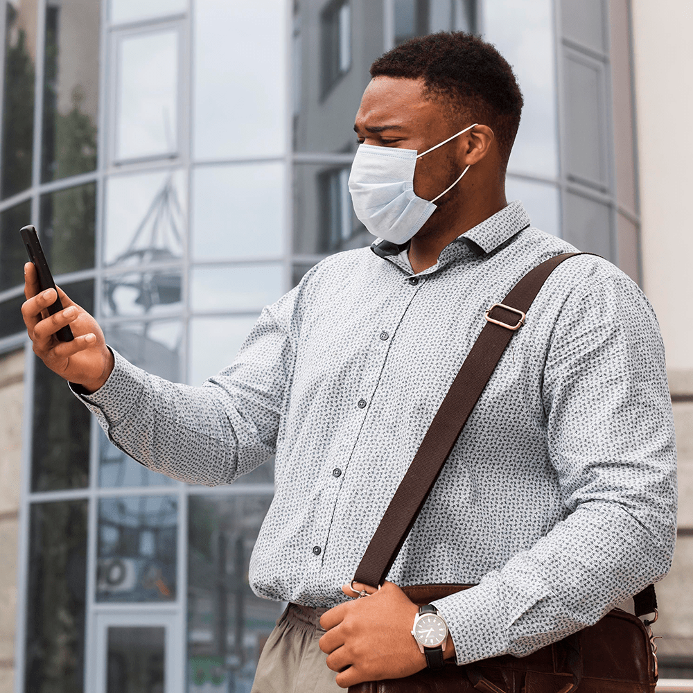 Man in face mask scowling at smartphone