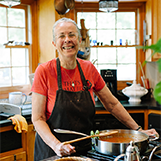 Leni Sorensen wearing a red T shirt and a black apron in a kitchen