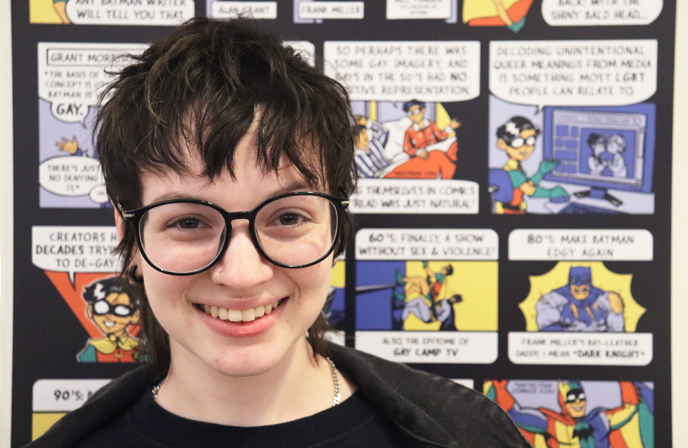 2023 Jurgen Comics Contest winner Rena Bridge in front of their comic exhibited on the first floor of James Branch Cabell Library.