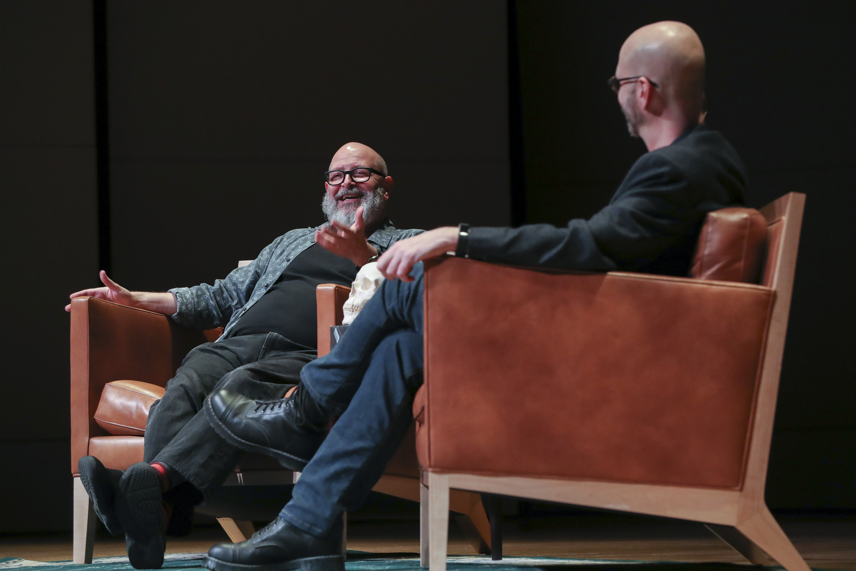 Mike Mignola and TyRuben Ellingson sitting in chairs, talking