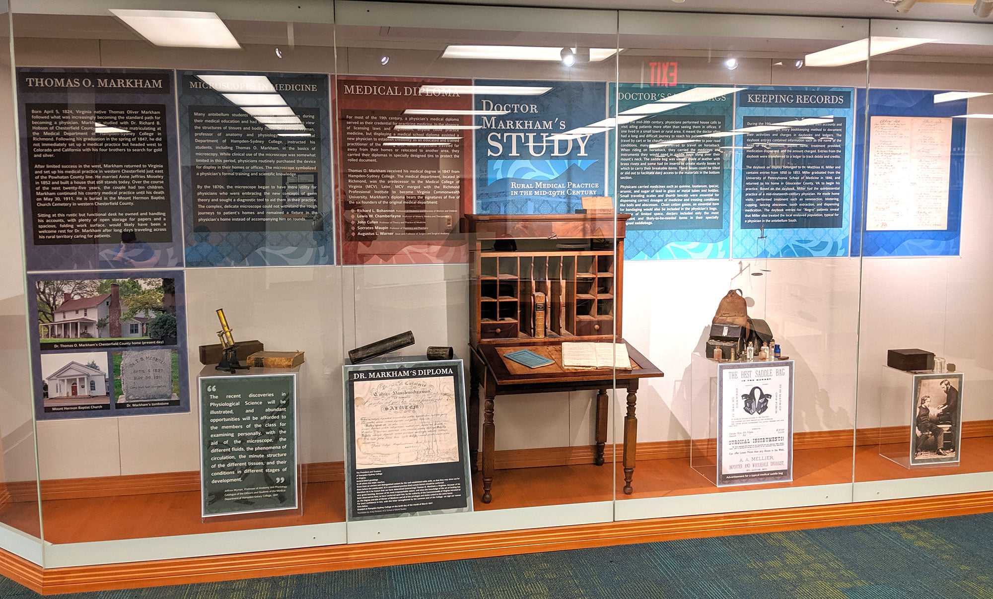 Photograph of exhibit featuring information panels and artifacts related to Dr. Markham, including his person desk