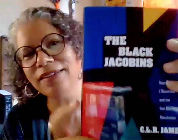 Ana Edwards holds up a book, The Black Jacobins, on Zoom