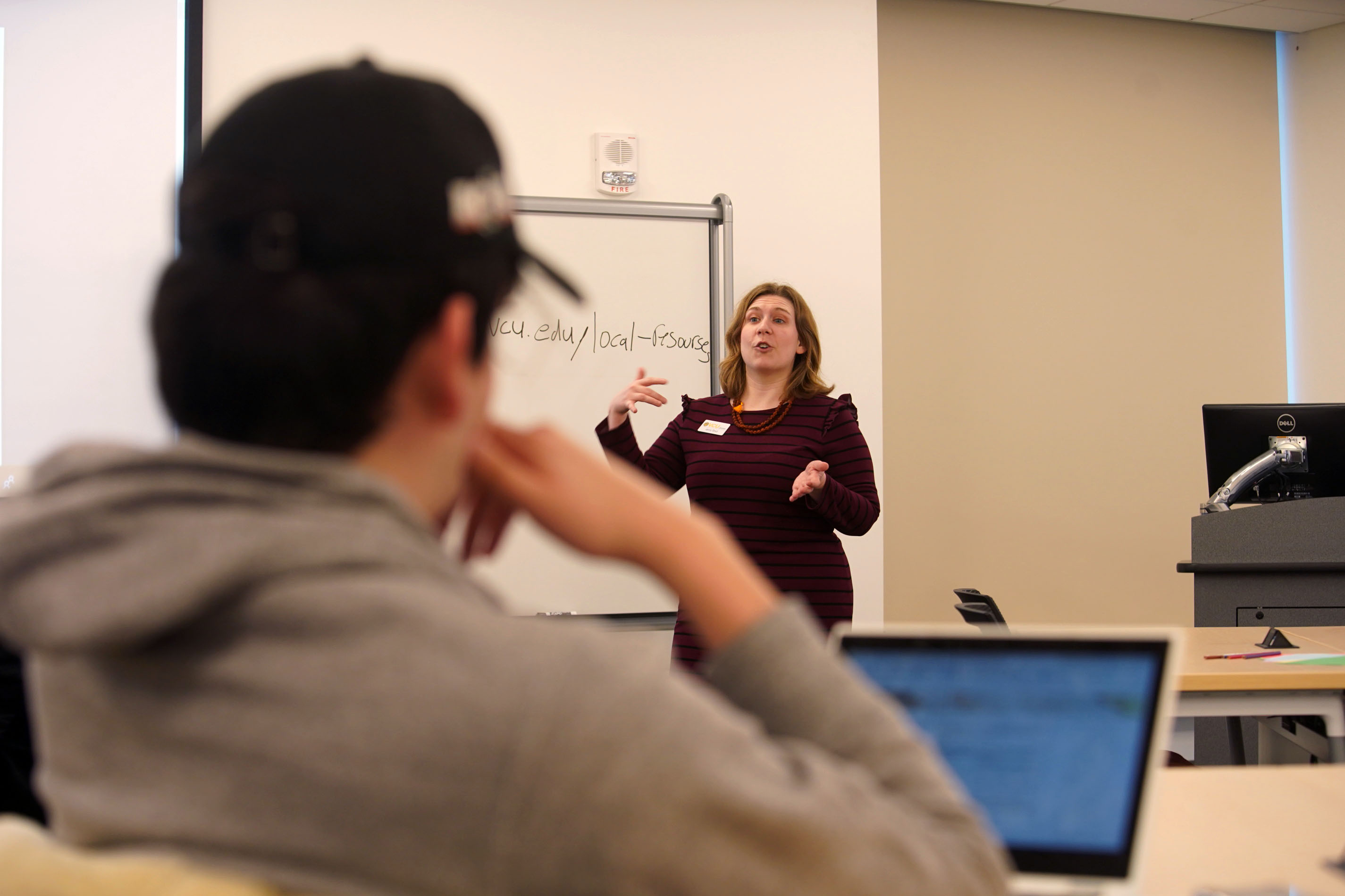 Jenny Stout teaching a class, with a student in the foreground, and a white board behind her.