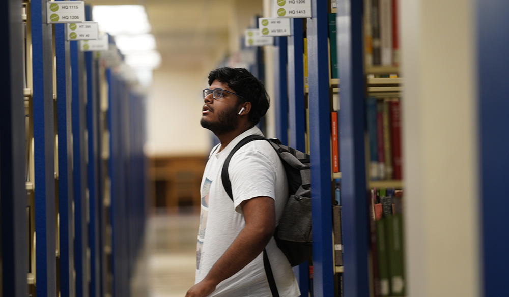 A student looking at the labels on the book shelves at James Branch Cabell Library.